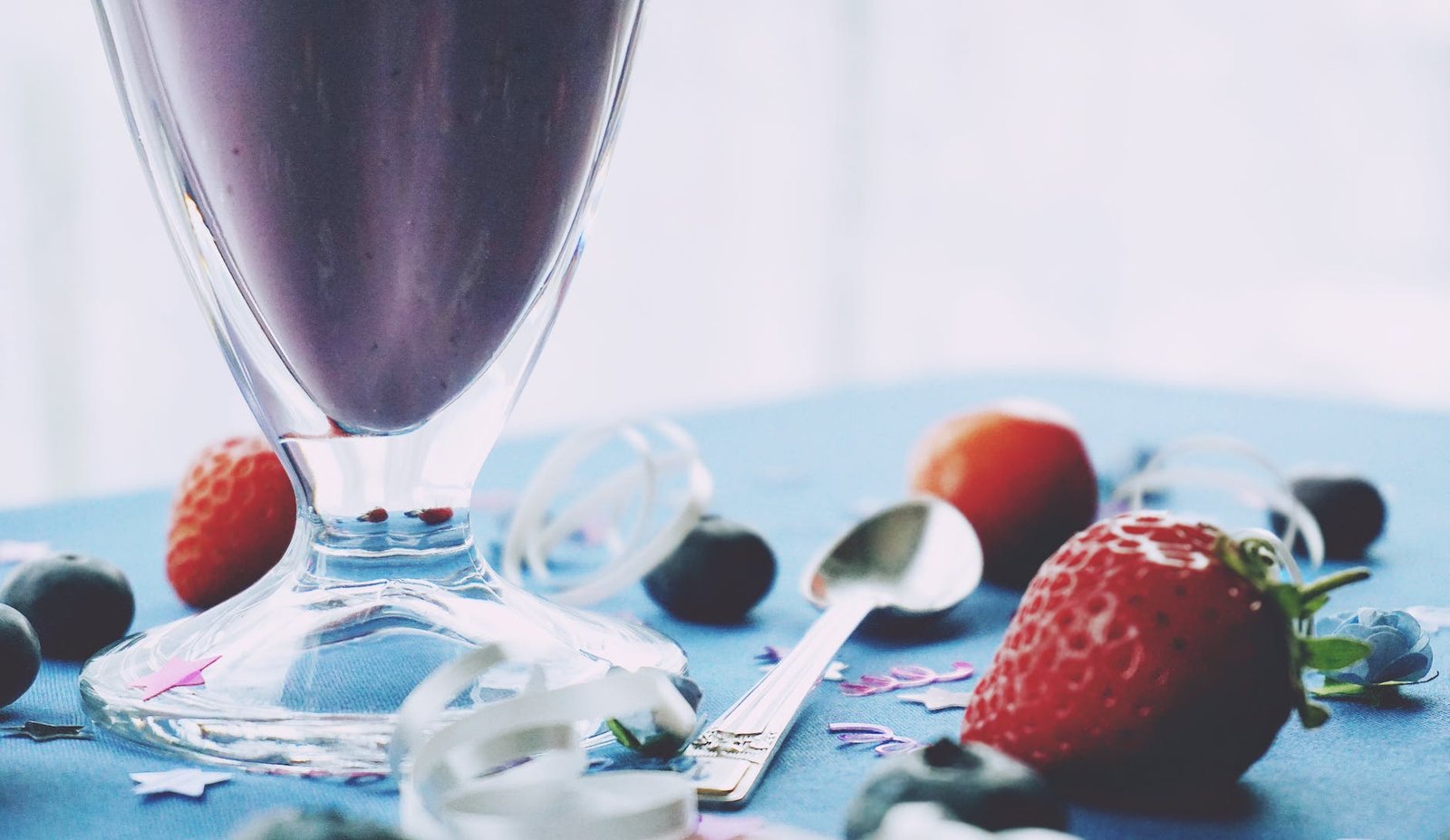 red strawberries beside footed cup with spoon