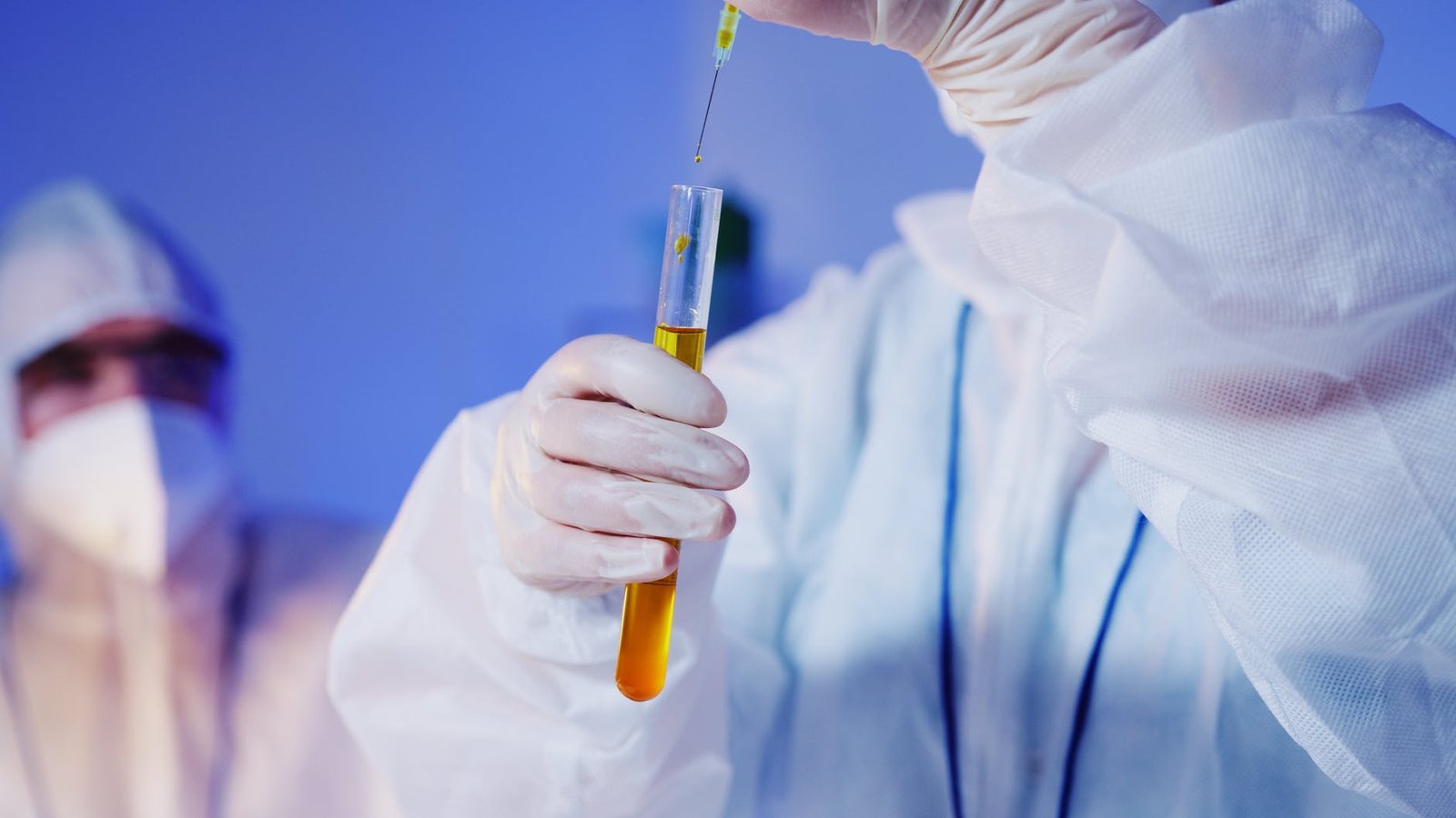 a person holding a test tube with yellow chemical and syringe