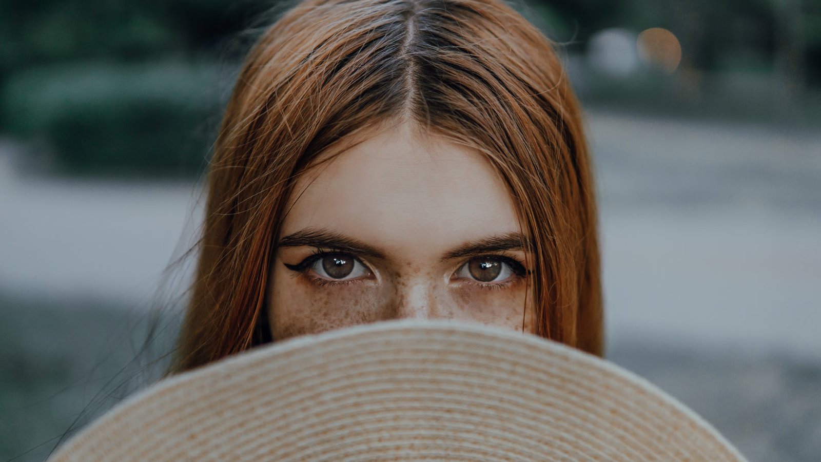 a woman covering her face with brown hat